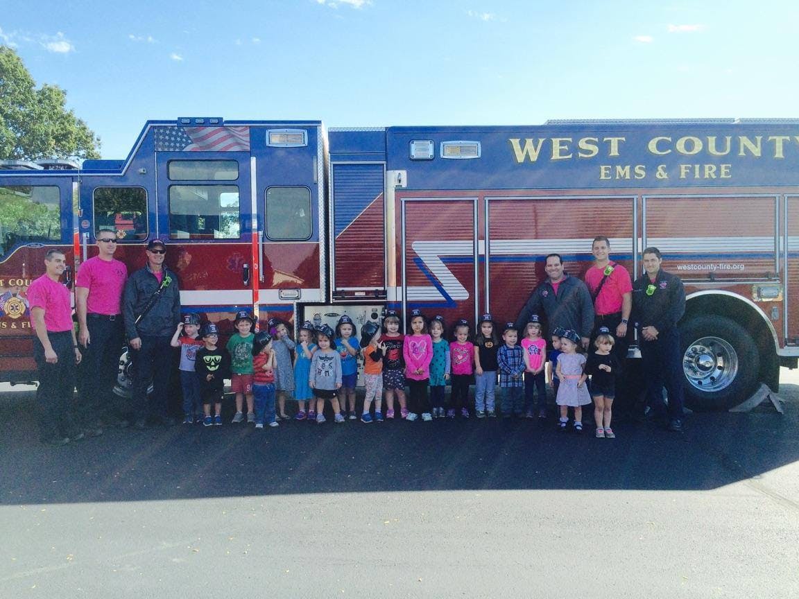 Adults and children standing in front of a fire truck