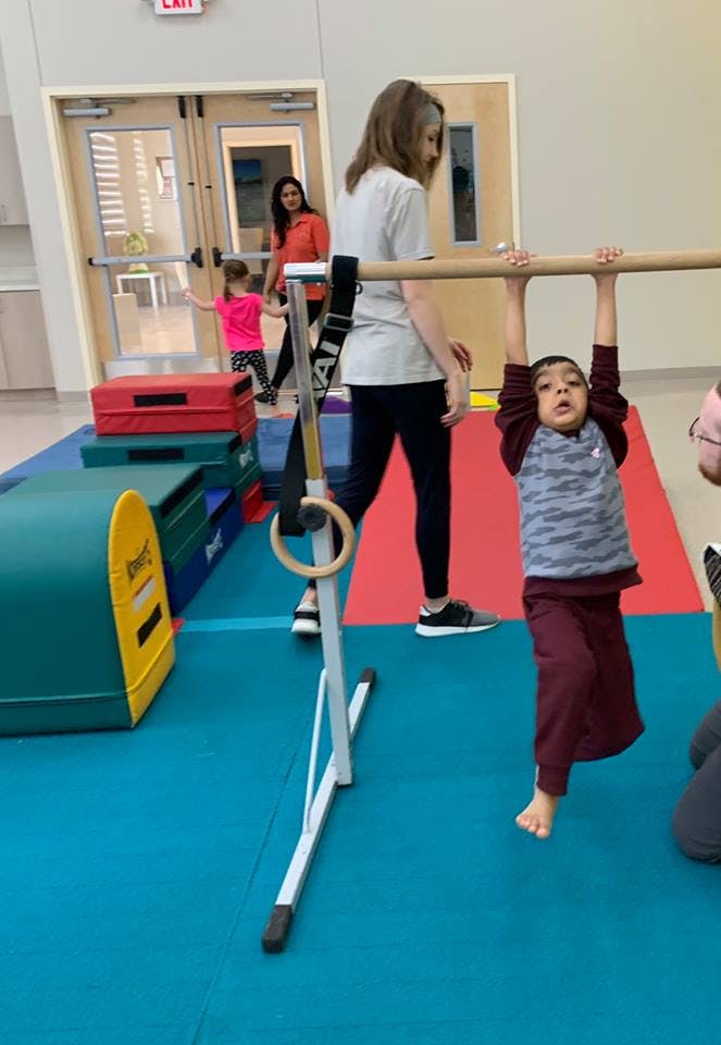Child hanging from a horizontal bar in a gym