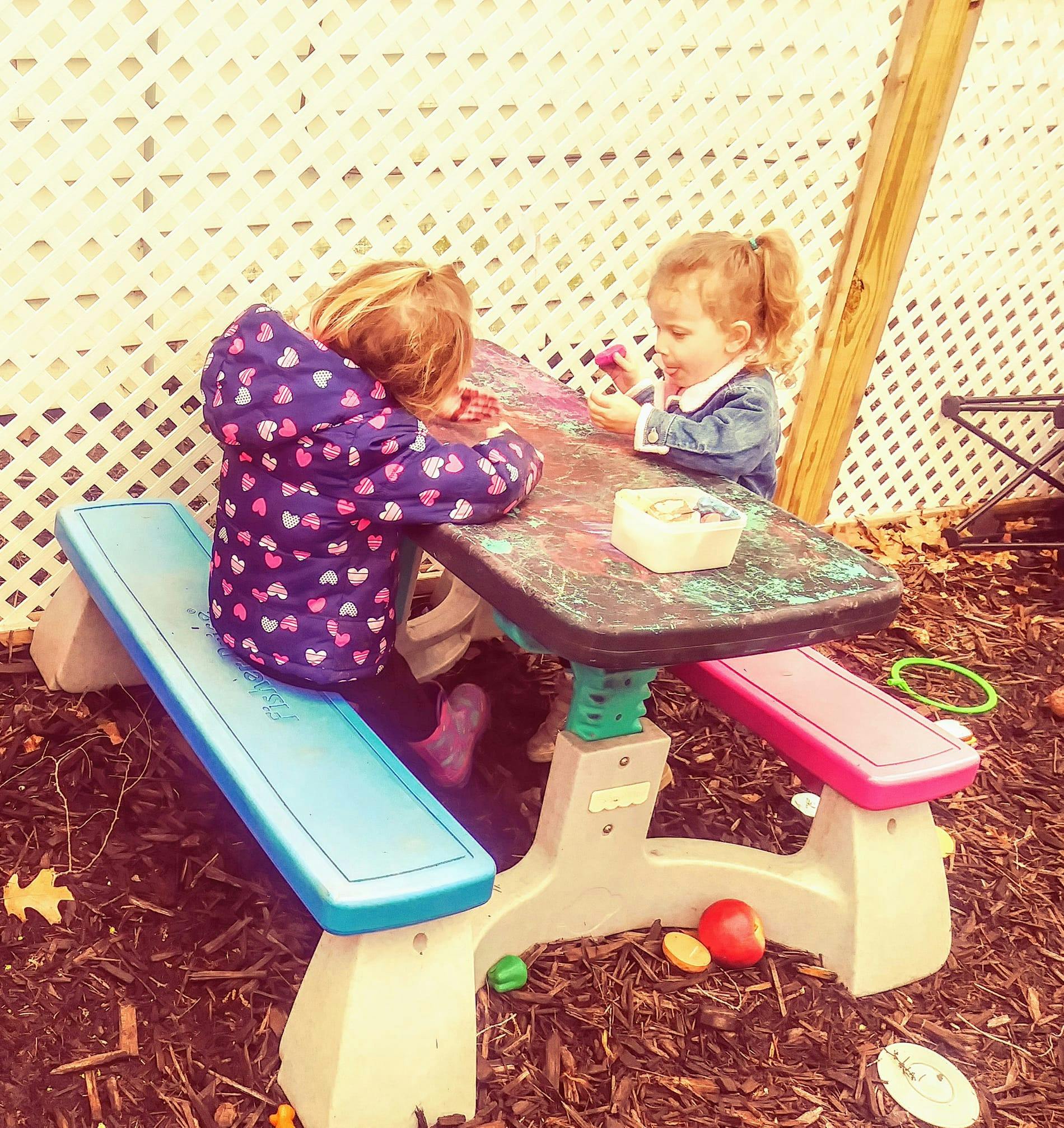 Two children playing at a small picnic table