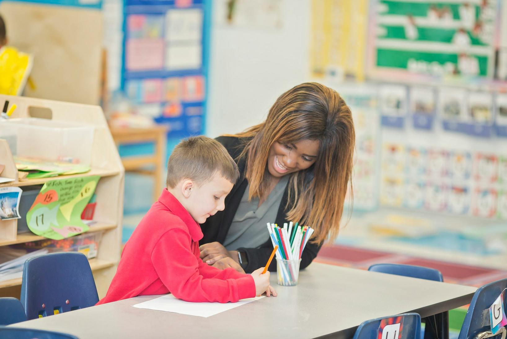 Adult and child drawing at a table in a classroom