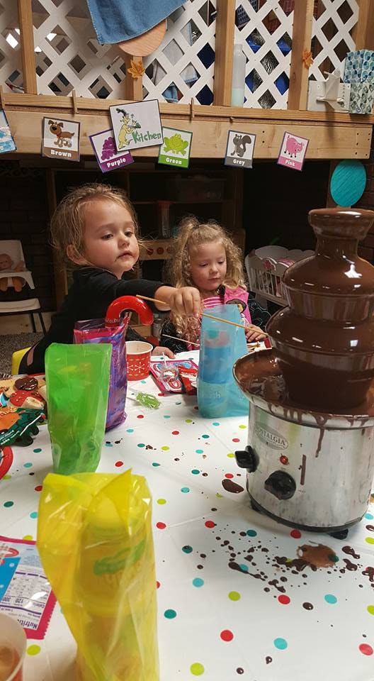Two children dipping items into a chocolate fountain