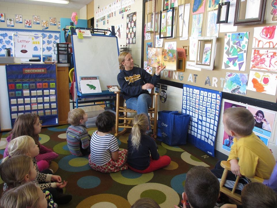 Person reading a book to children in a classroom