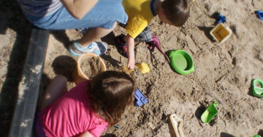 People playing in a sandbox with toys