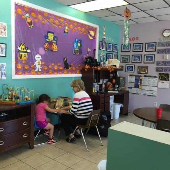 Adult and child sitting at a table in a room with Halloween decorations