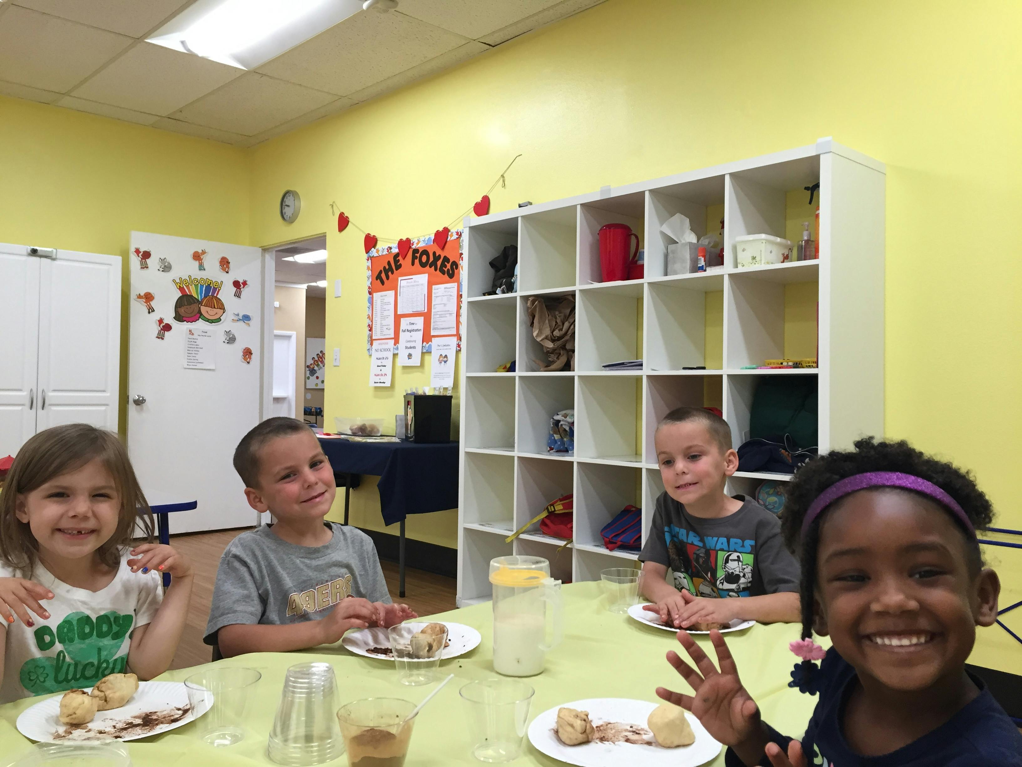 Four children sitting at a table in a classroom