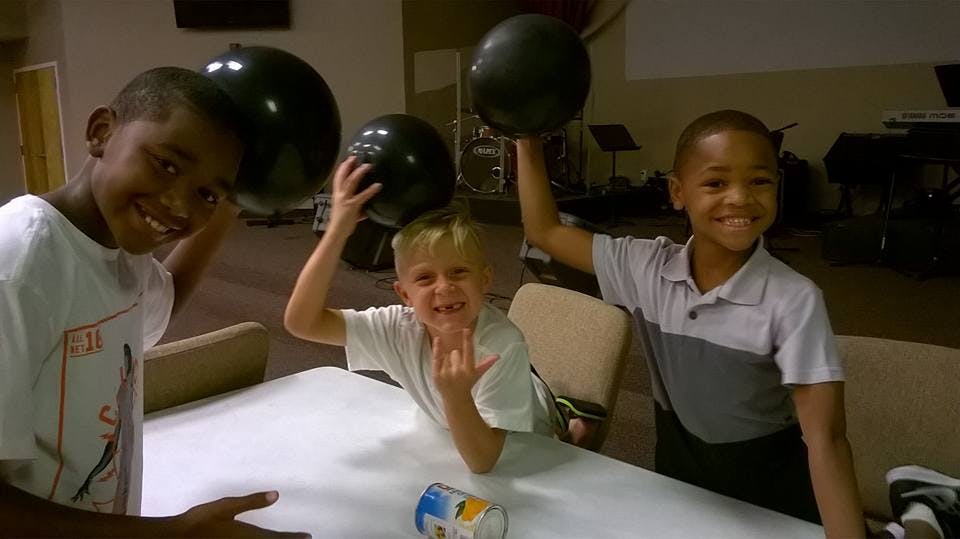 Three children holding up black balloons