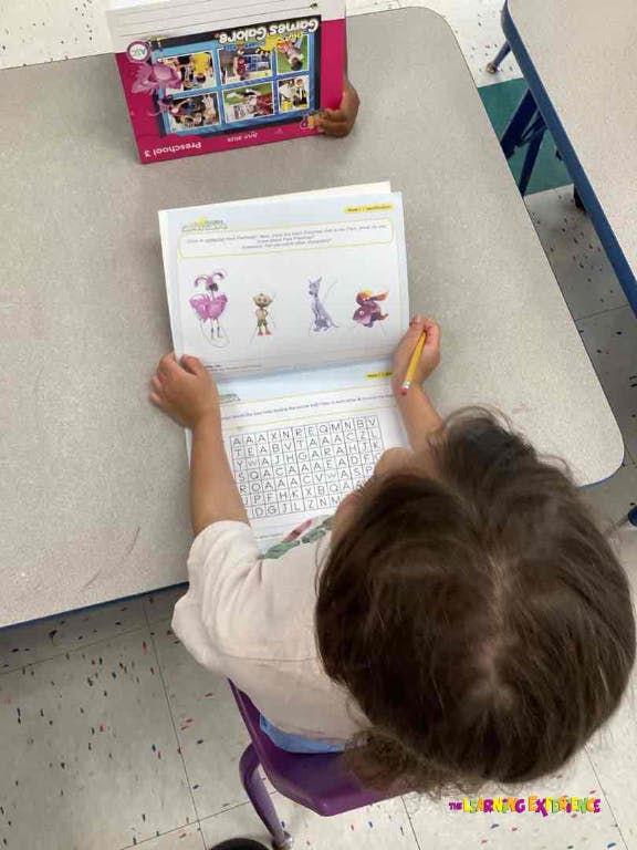 Child at a desk working on a worksheet with cartoon characters