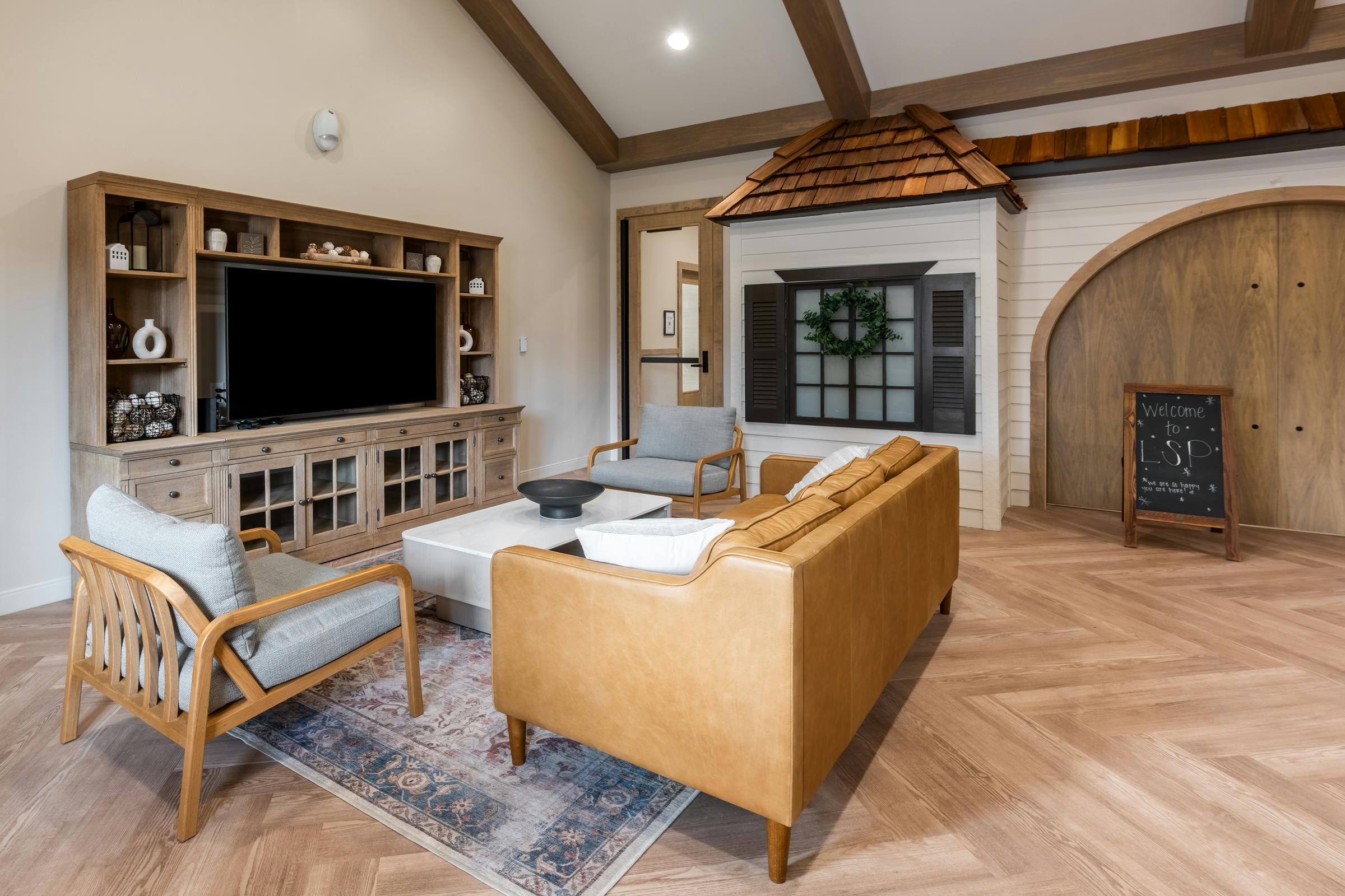 Living room with a large TV, sofa, and armchairs