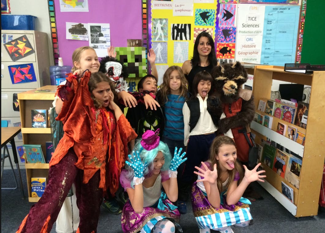 Adult and children in costumes posing in a classroom