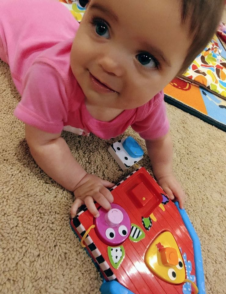 Child playing with a colorful activity toy on the floor