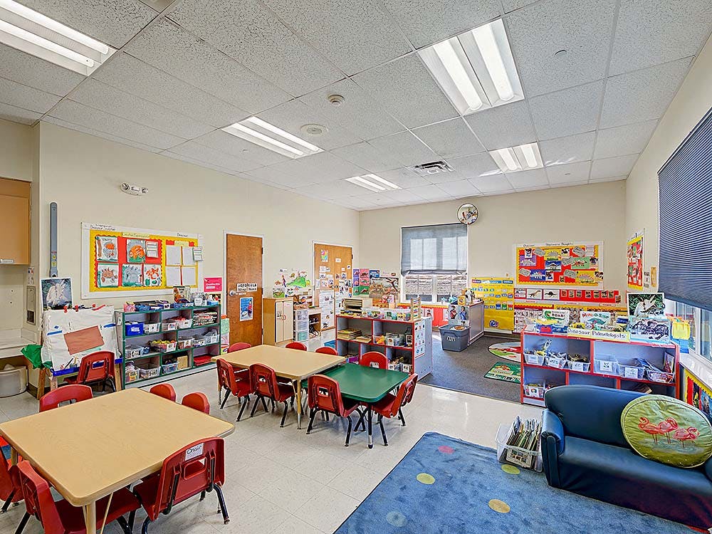 Classroom with small tables and chairs, shelves, and decorations