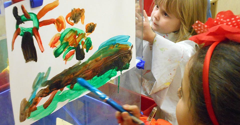 Two children painting on an easel