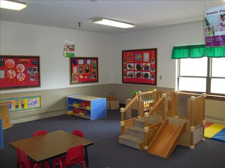 Classroom with play structure, small table and chairs, and bulletin boards