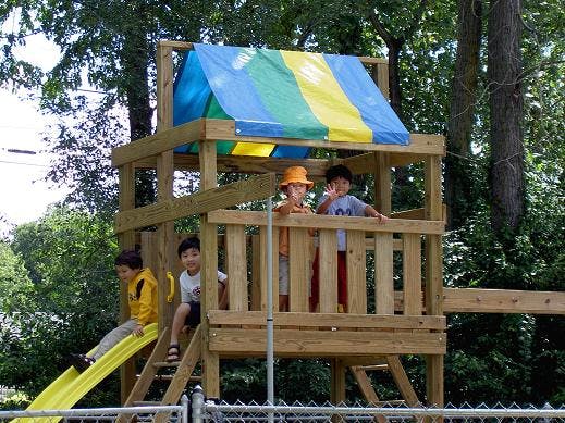 Children on a wooden playground structure with a slide
