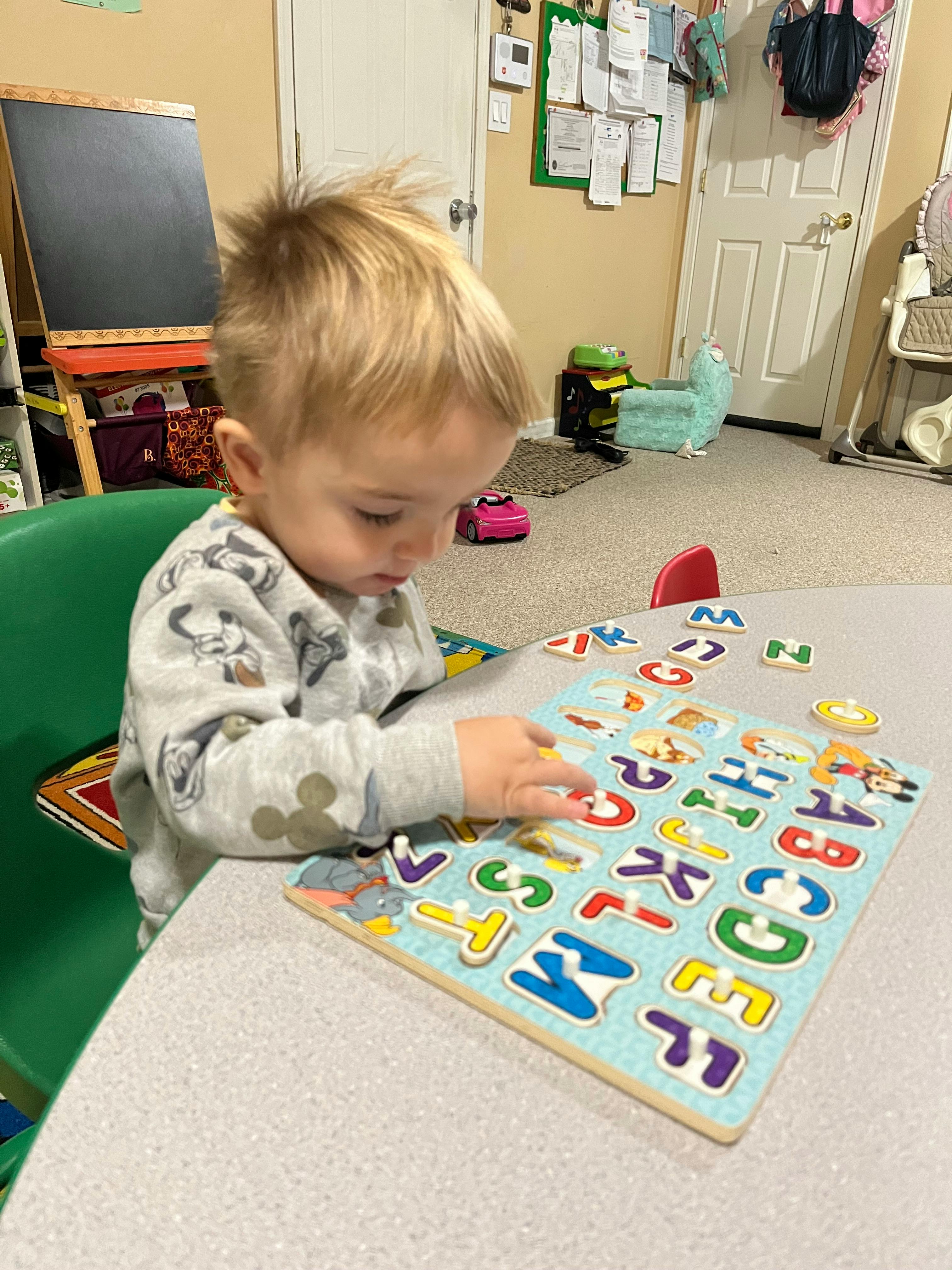 Child playing with an alphabet puzzle at a table
