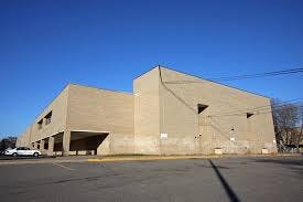 Large building with a flat roof and a parking lot in front