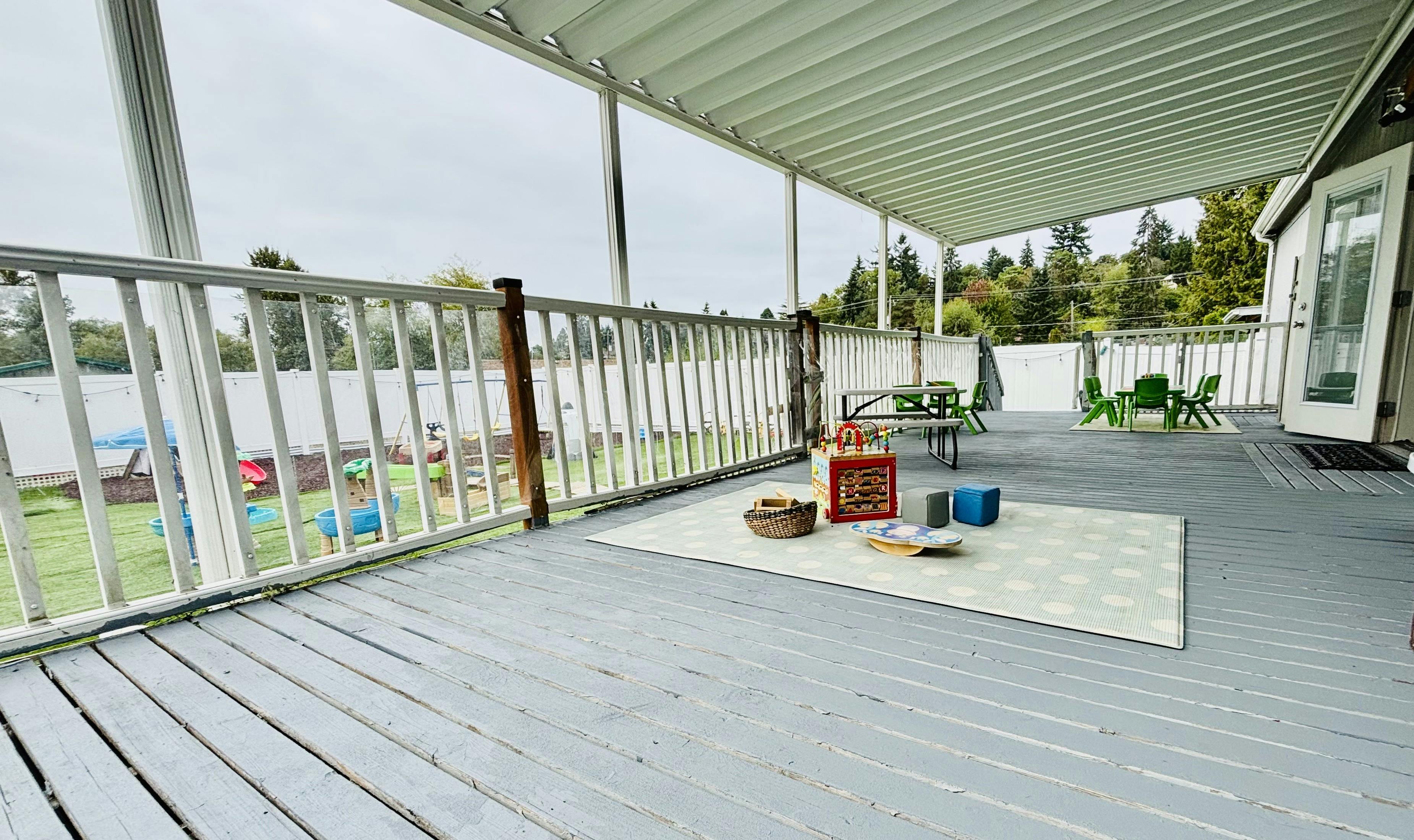 Covered outdoor deck with a white railing overlooking a grassy area