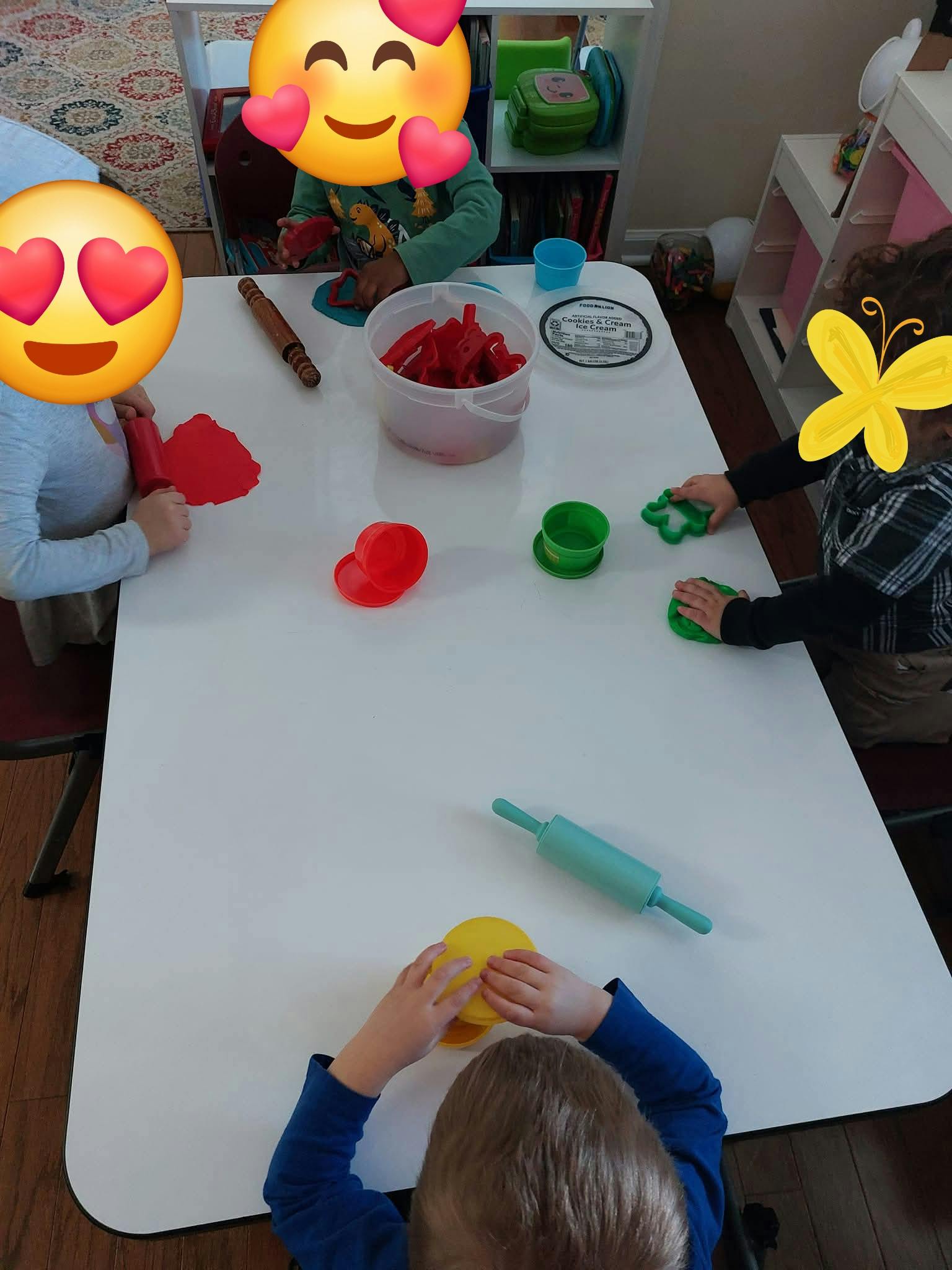 Children playing with modeling clay and cookie cutters at a table