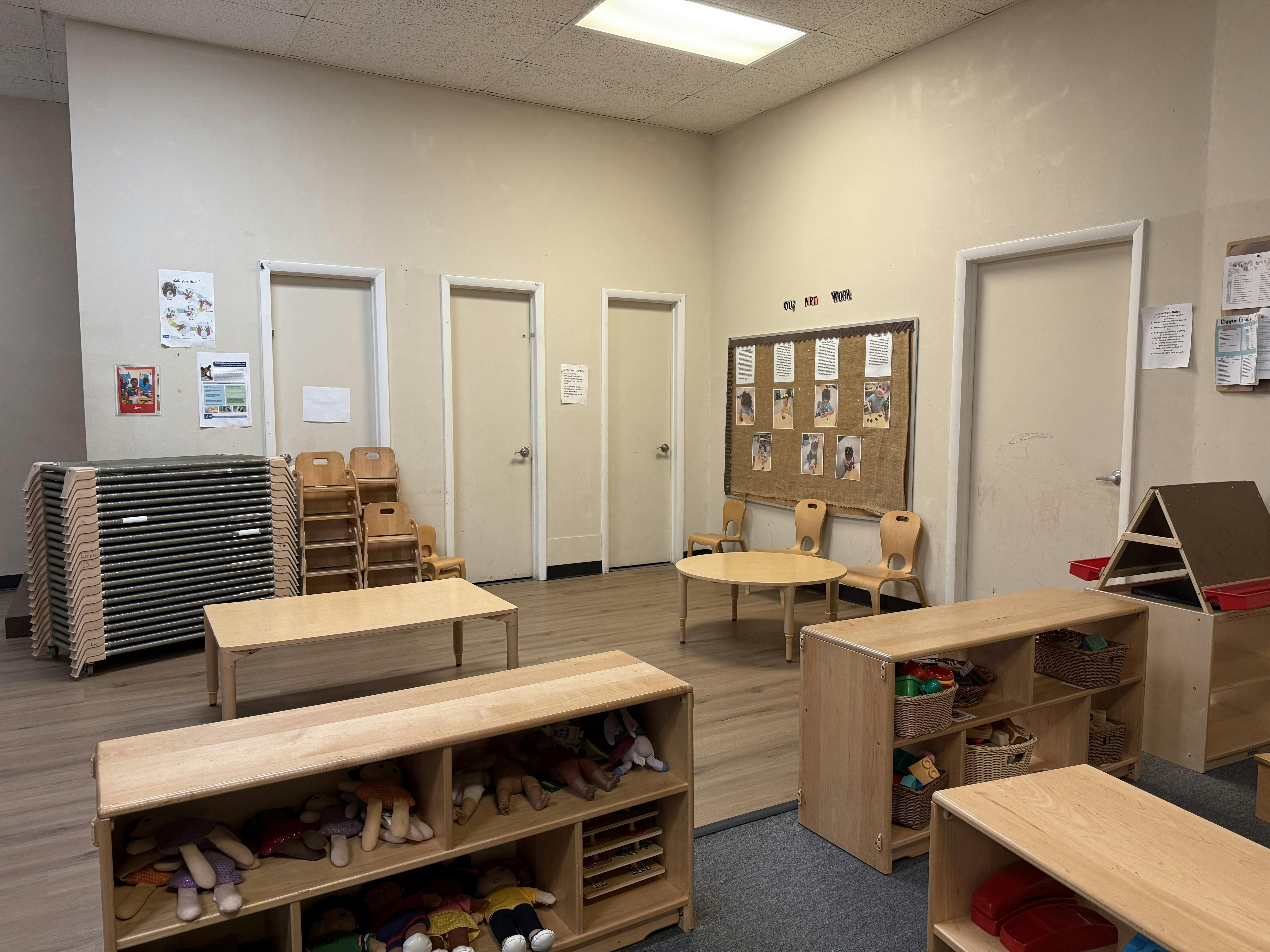 Empty classroom with wooden shelves, tables, and chairs