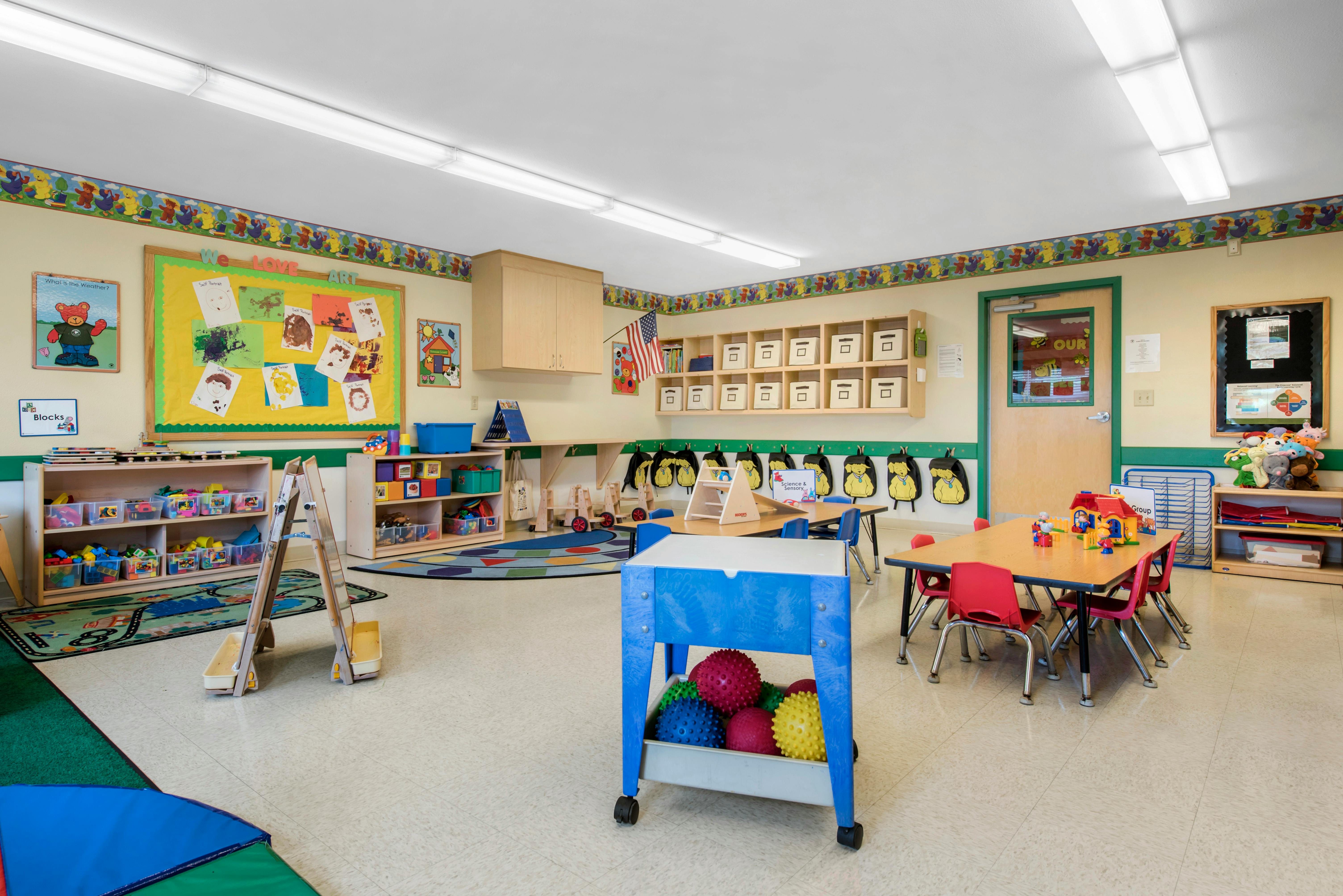 Classroom filled with child-sized tables and chairs, shelves, and learning materials