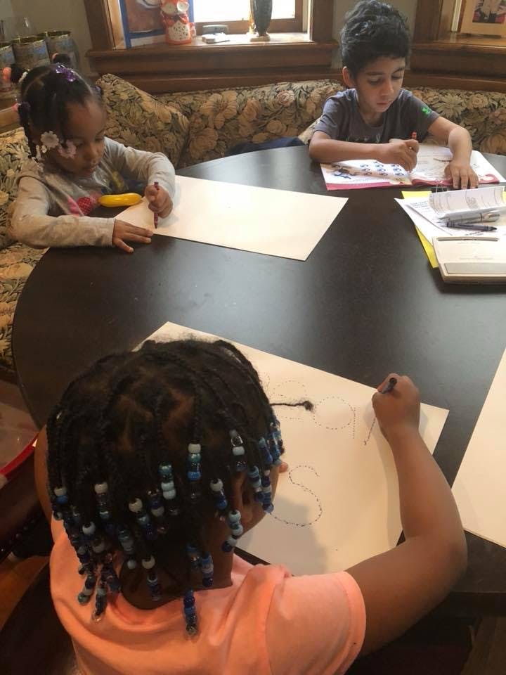 Three children drawing at a table