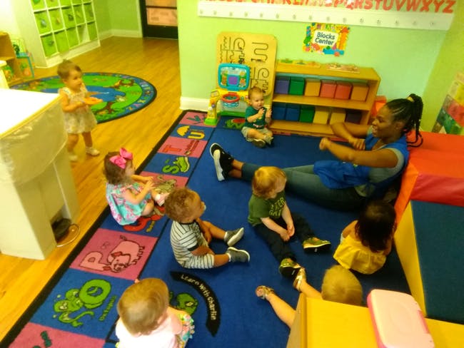 Adult and children sitting on a rug in a classroom