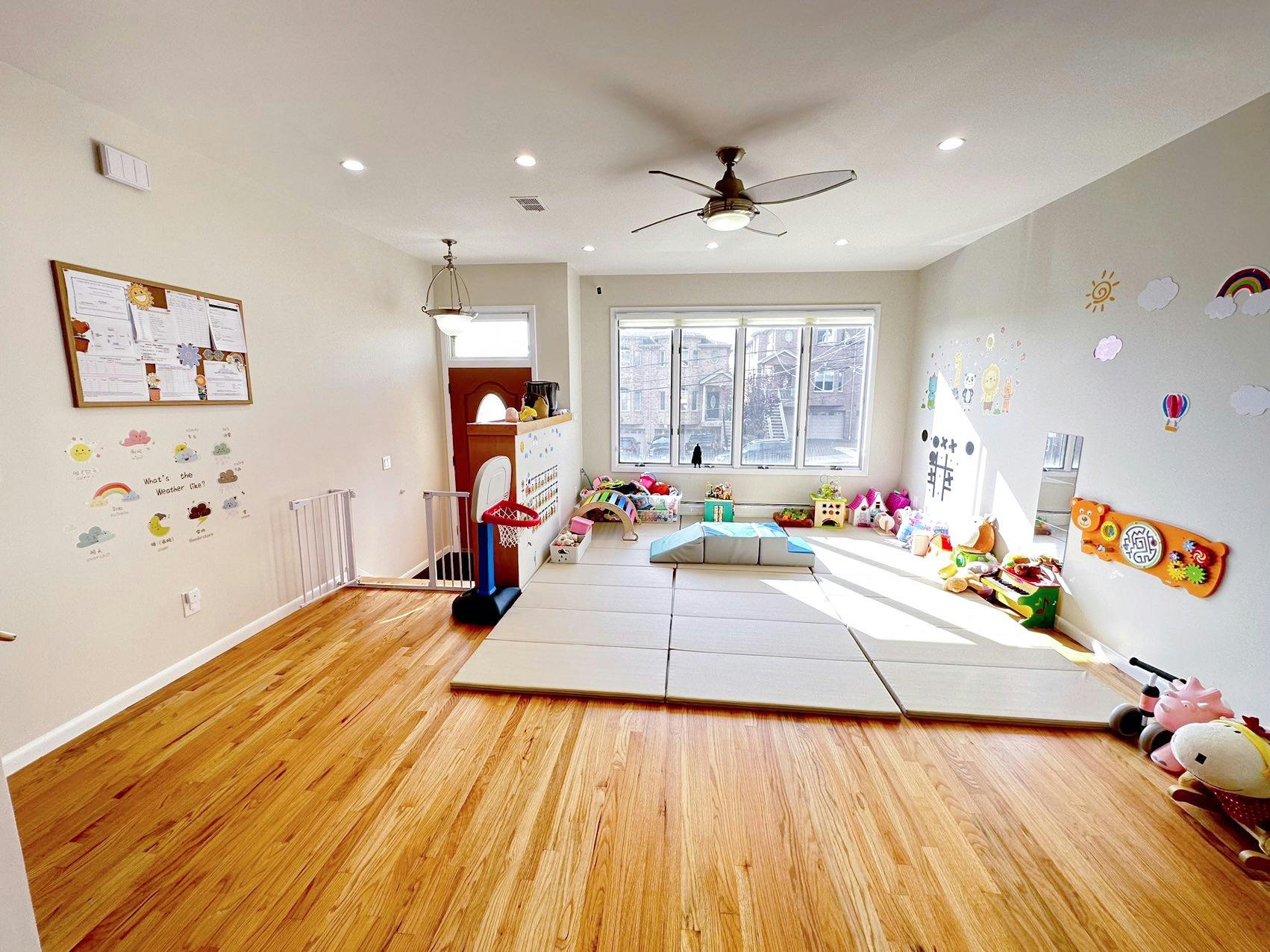 Playroom with hardwood floors, play mats, and toys