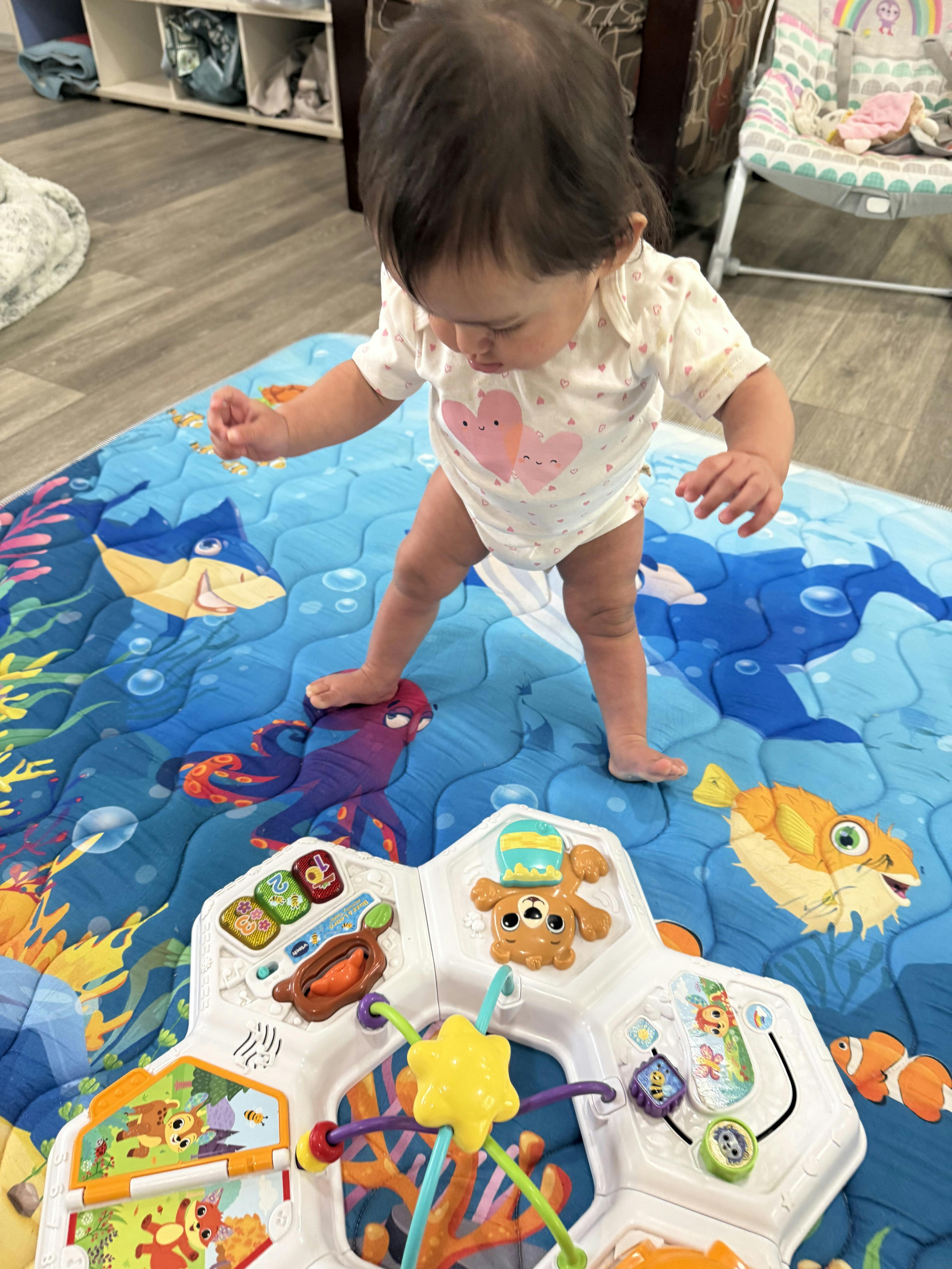 A child standing on an ocean-themed play mat in front of a toy