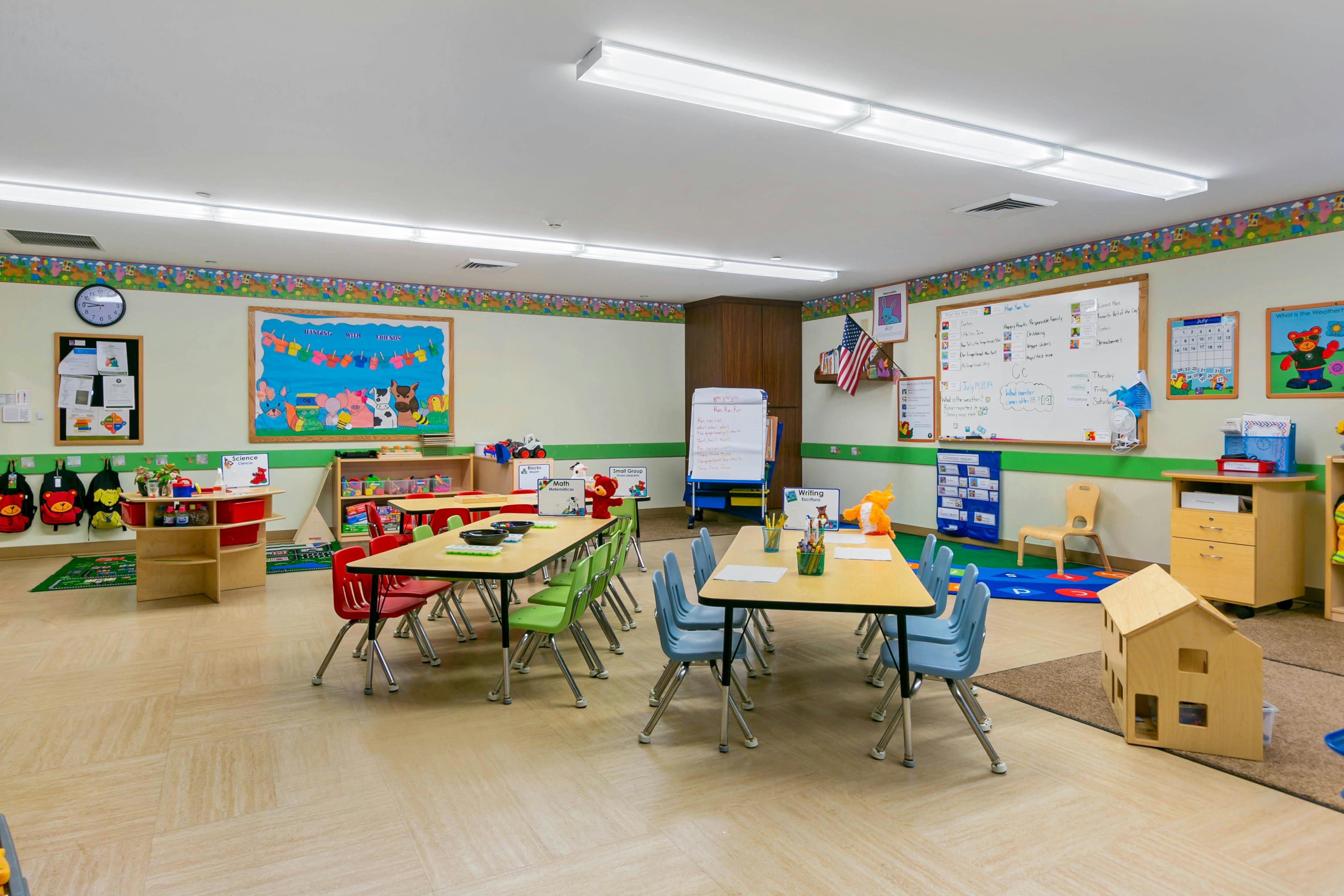 Classroom with child-sized tables and chairs, whiteboards, and educational posters