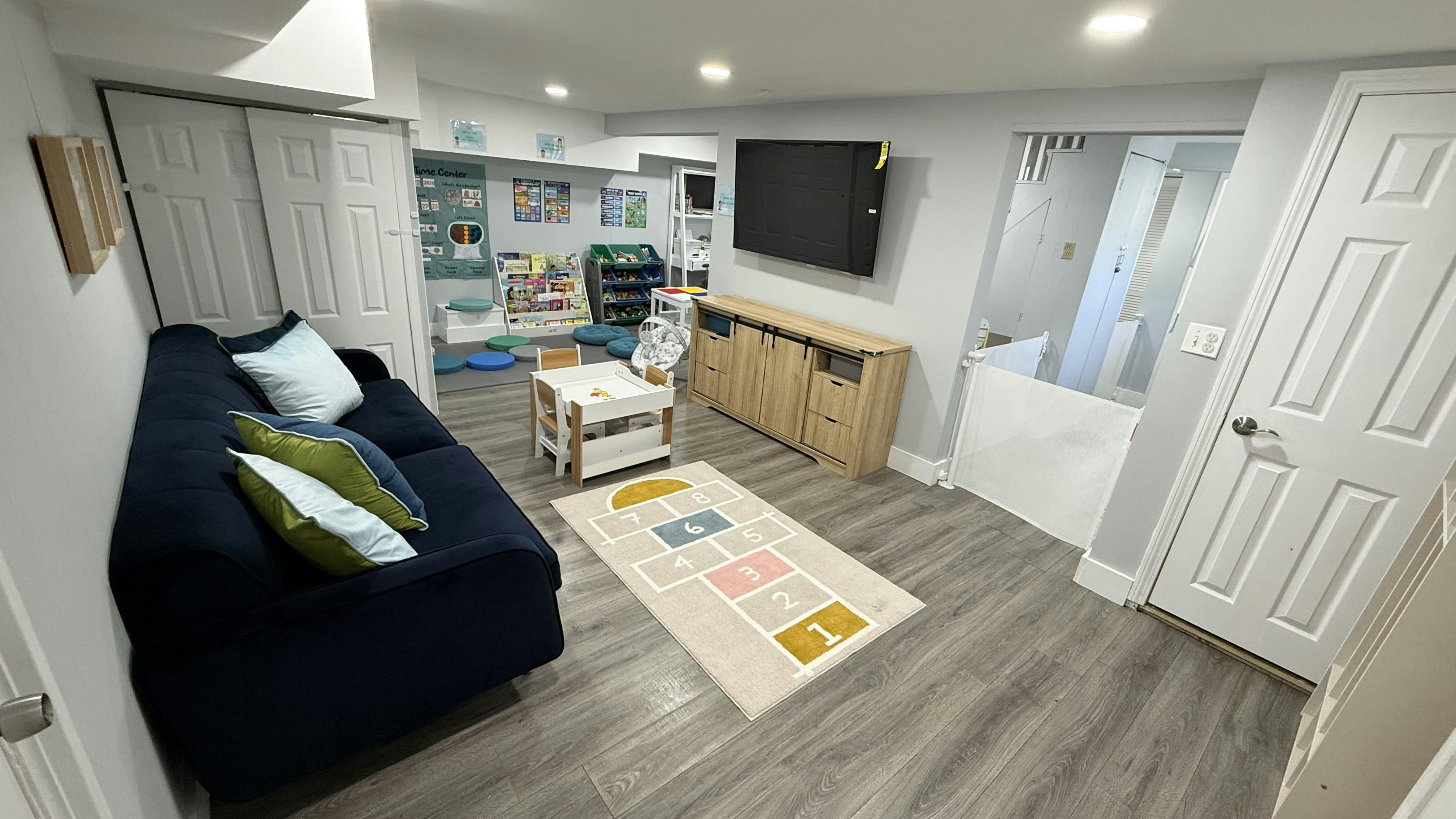 Living room with a dark blue sofa, television, and play area