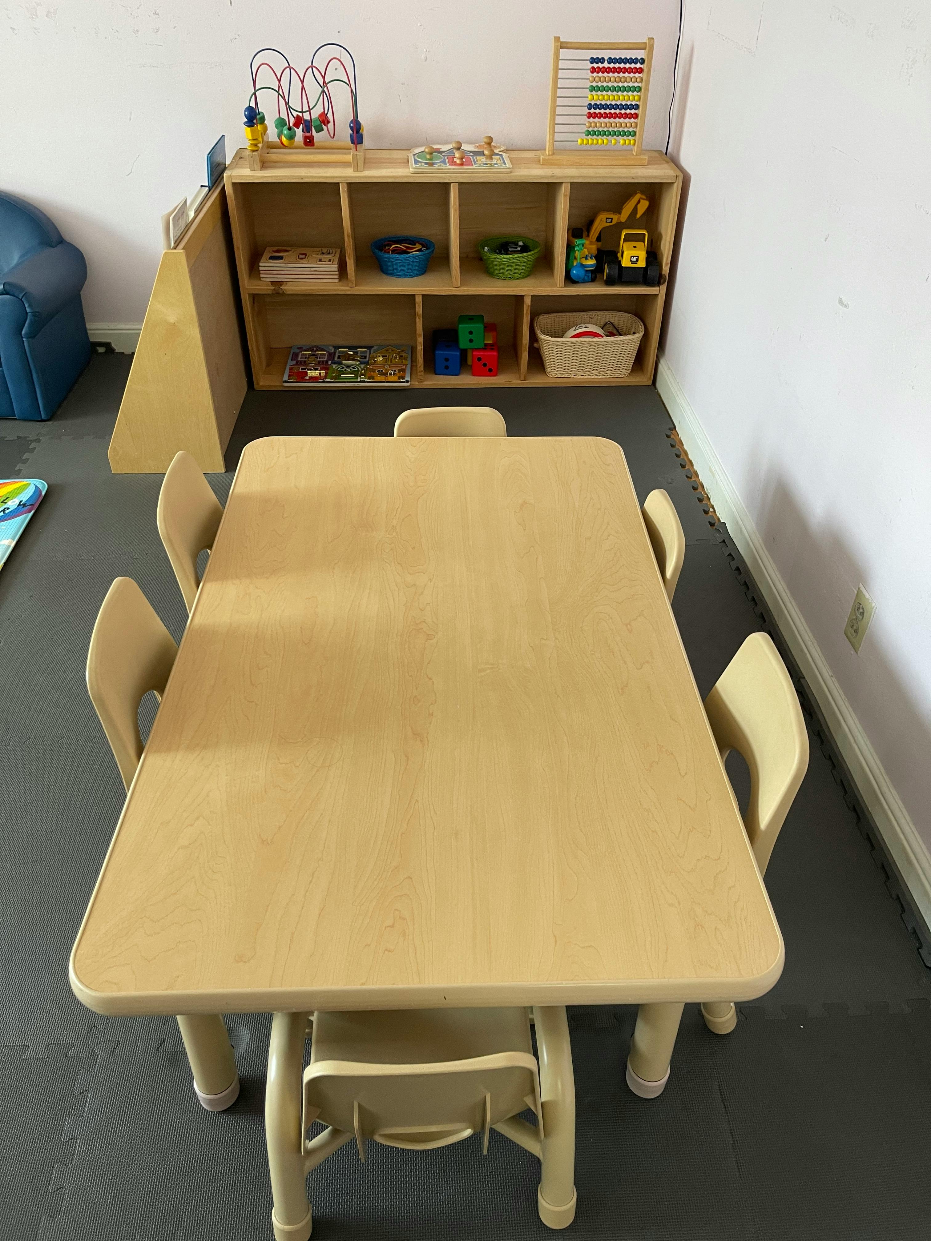 Children's table and chairs in a classroom with a toy shelf