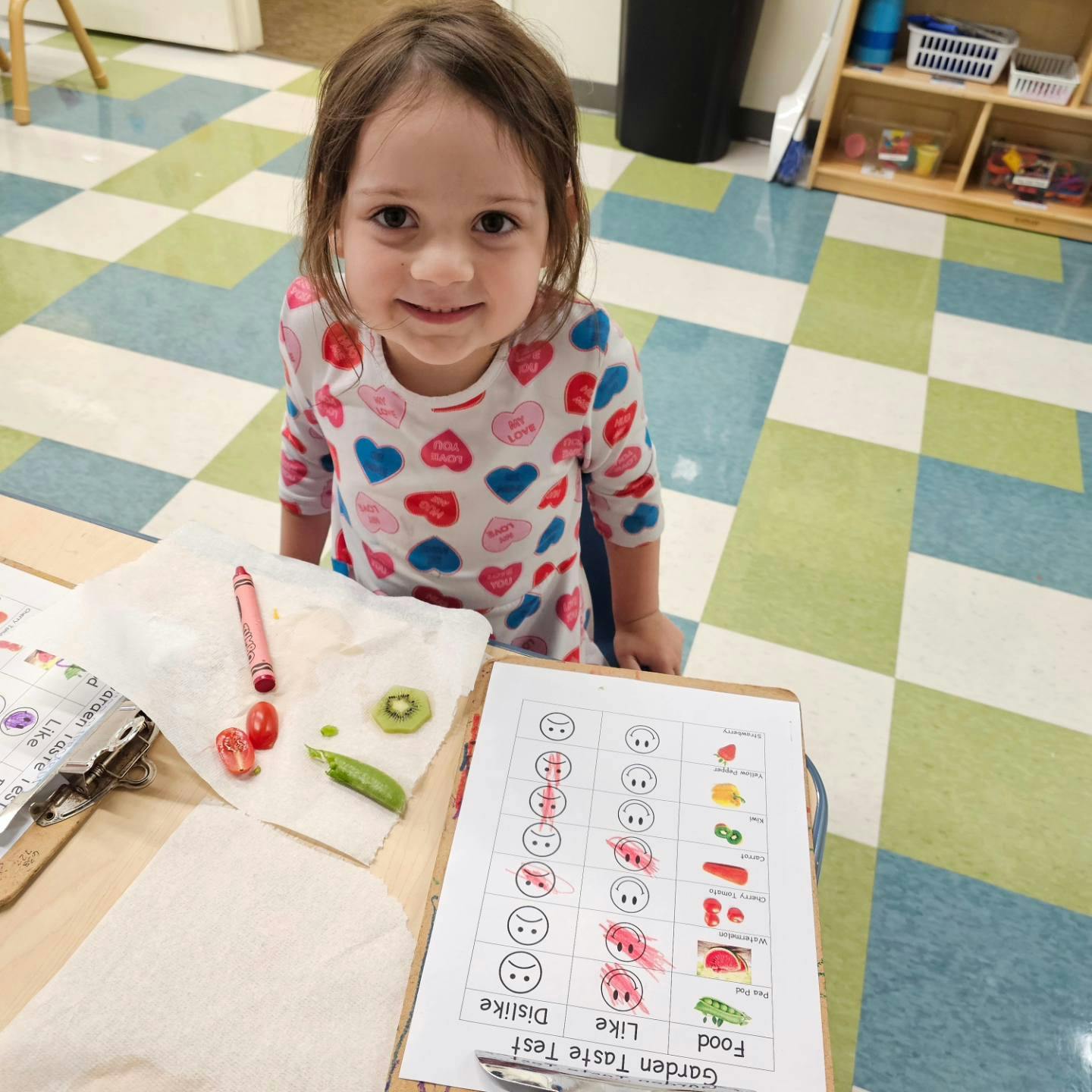 Child at a table with a "Garden Taste Test" chart and food samples