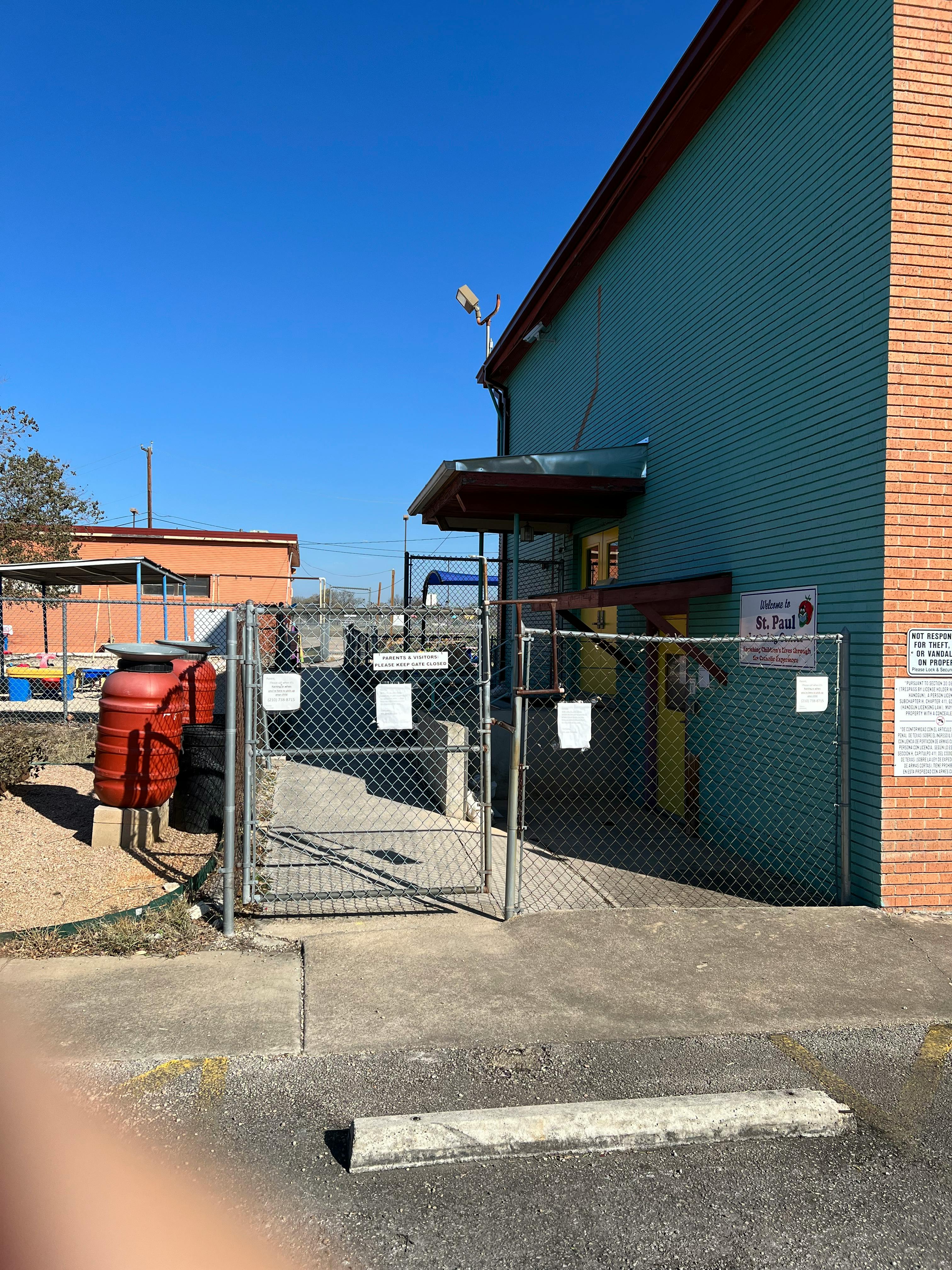 Chain link fence gate next to a building with a blue wall