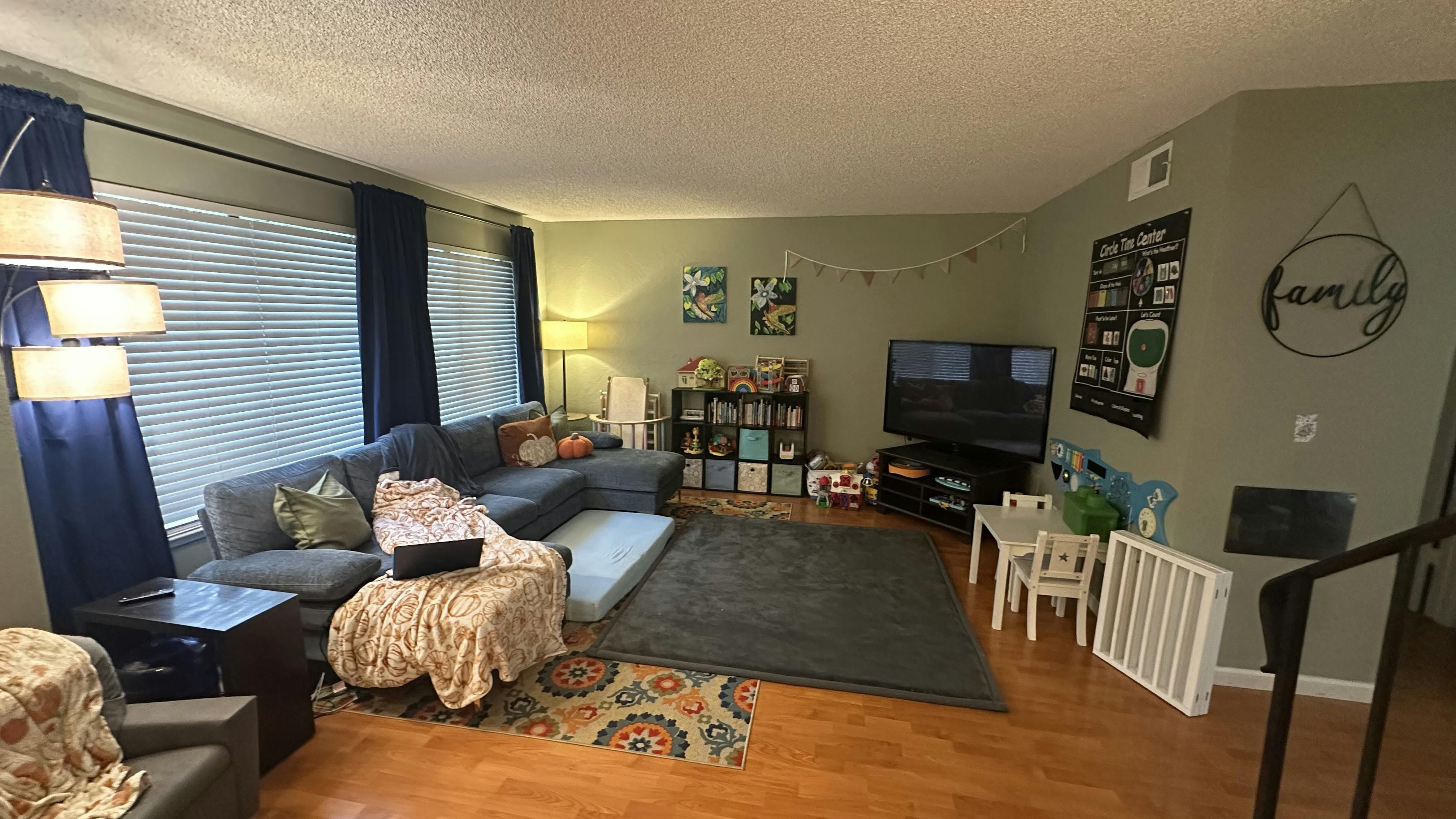 Living room with a large sectional sofa, television, and children's play area