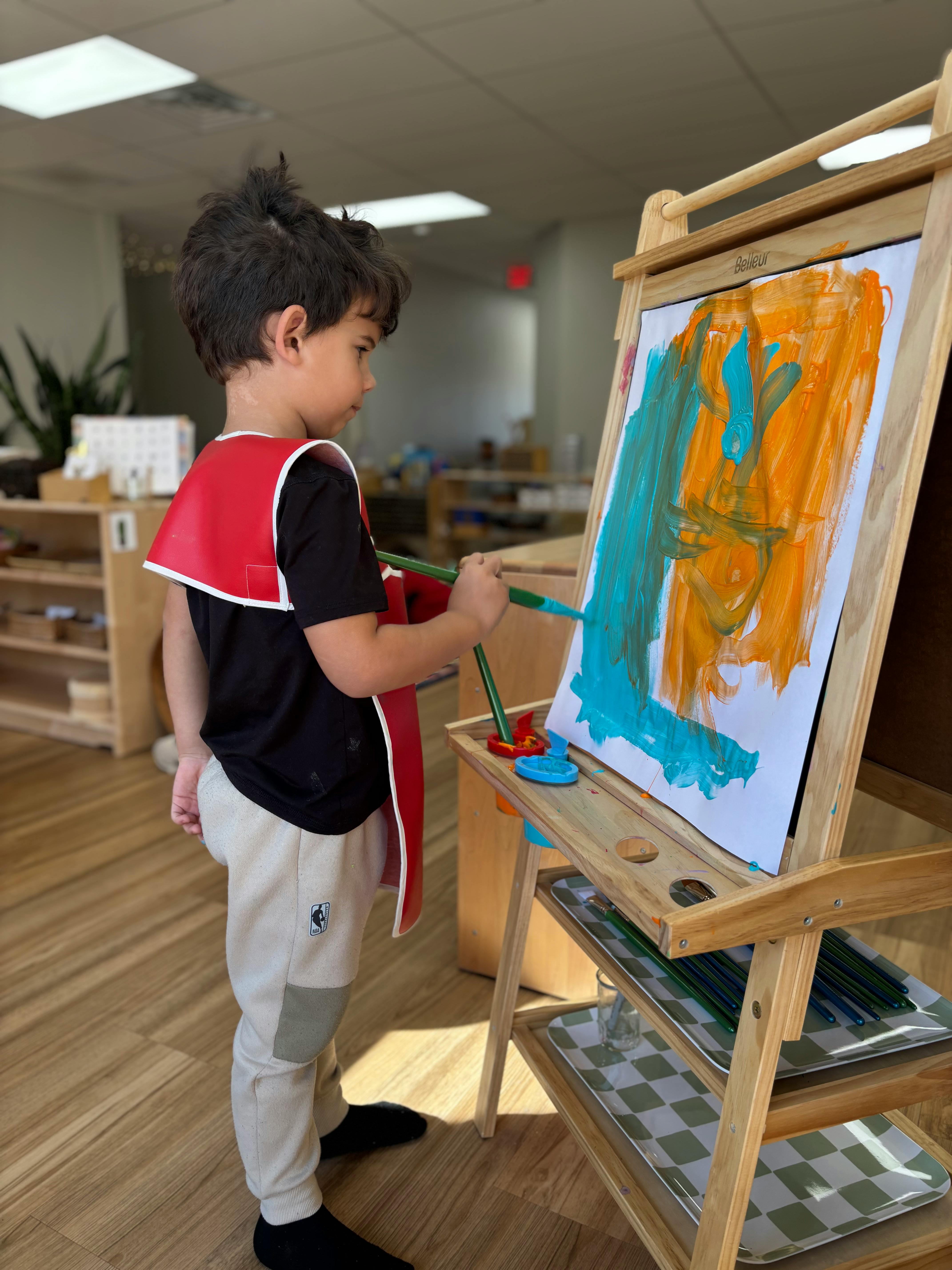 Child painting on an easel in a classroom