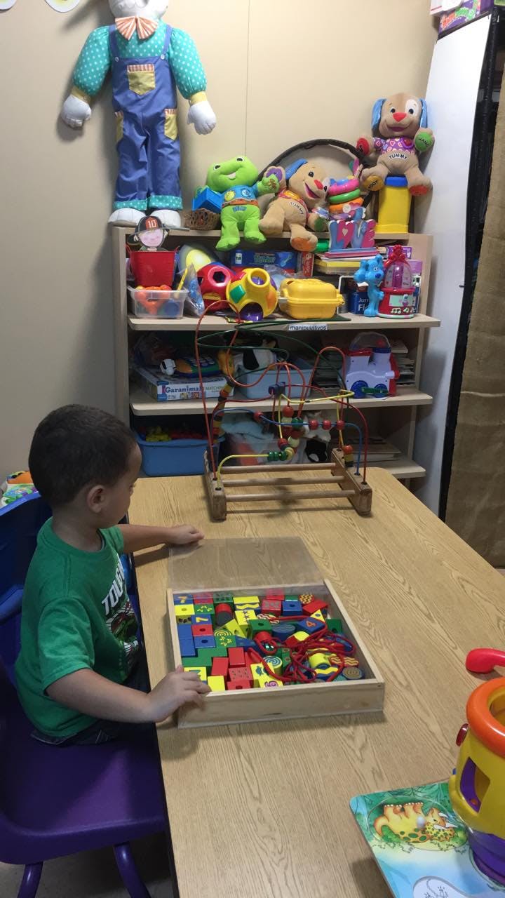 Child sitting at a table with a box of colorful blocks
