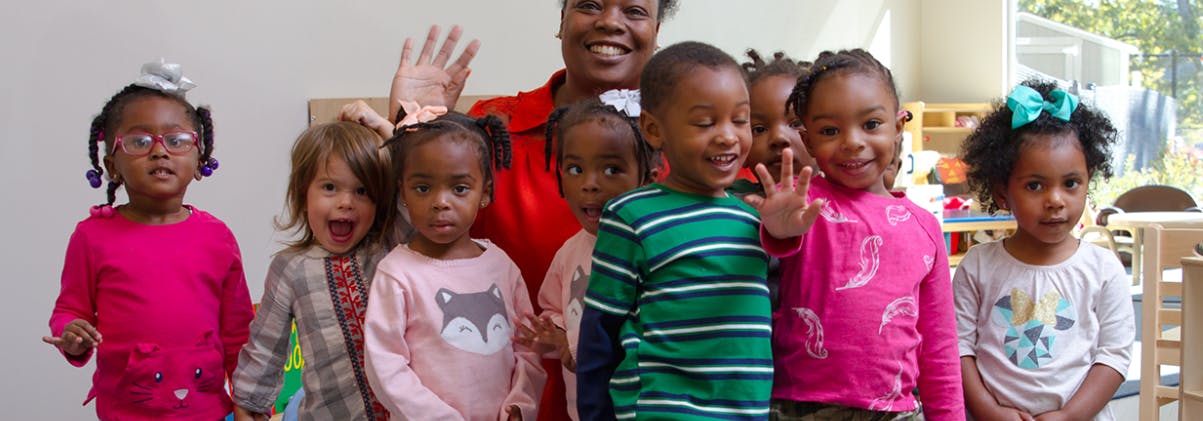 Adult and group of children waving