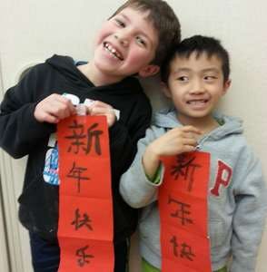 Two children holding red banners with Chinese characters