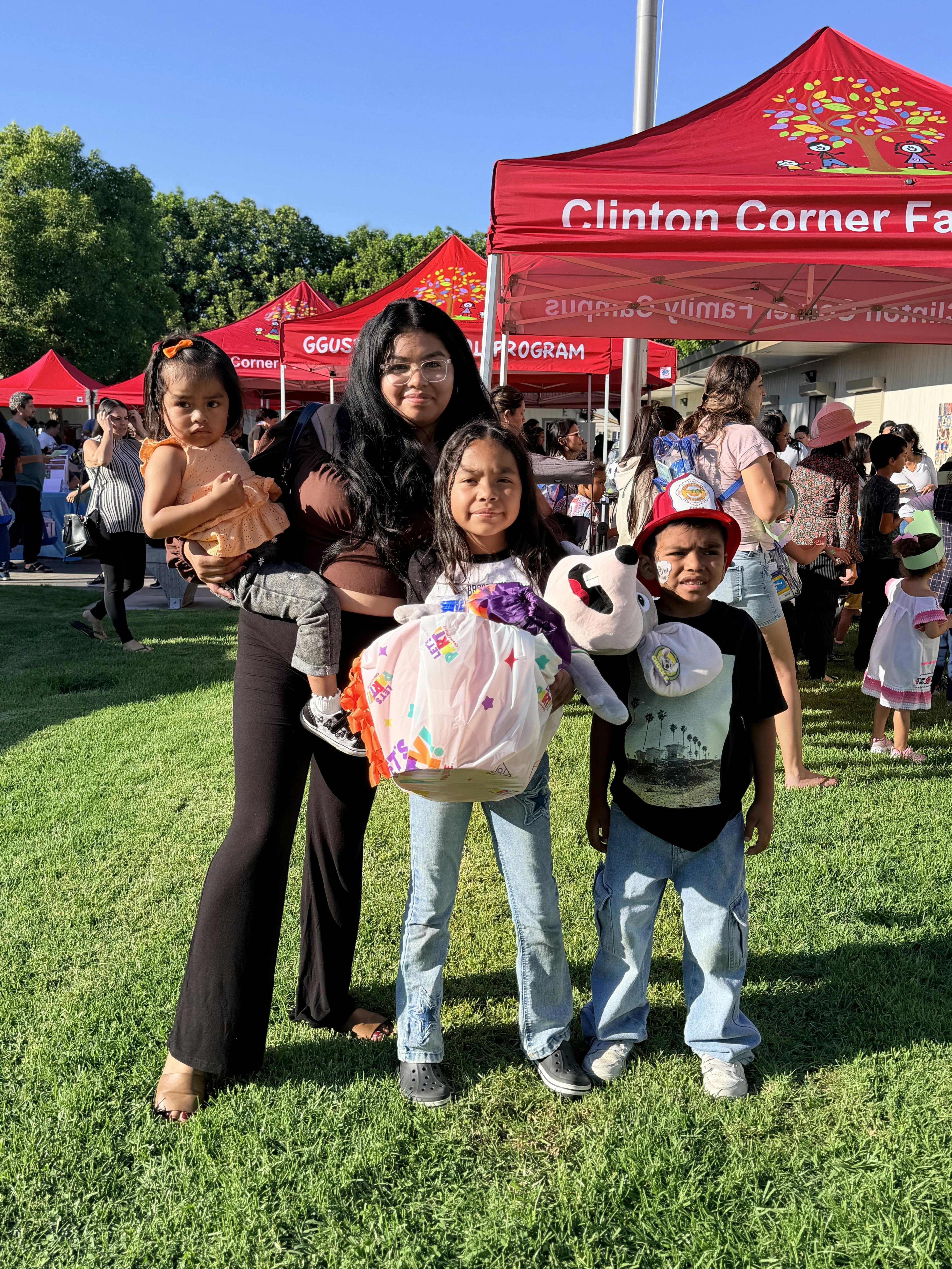 A person holding a child and standing next to two children at an outdoor event