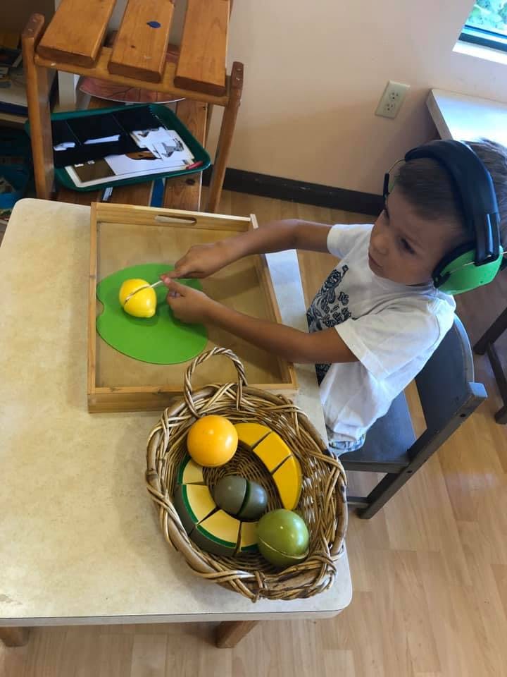 Child wearing headphones cutting a toy lemon with a knife