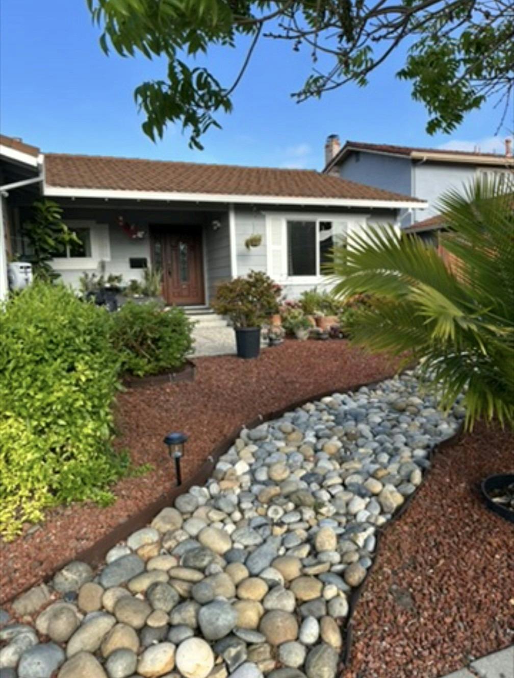 Single story house with a brown roof and a rock garden path