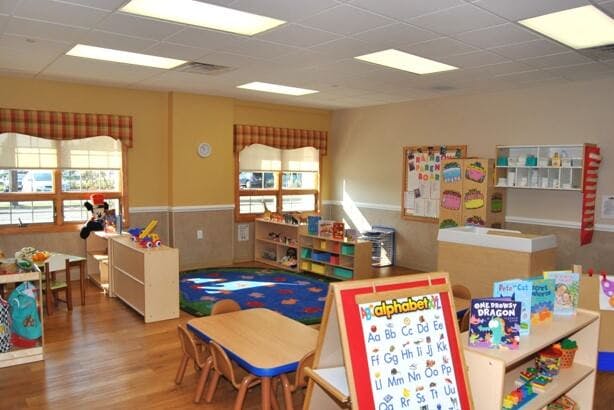 Empty classroom with small tables, chairs, and learning materials