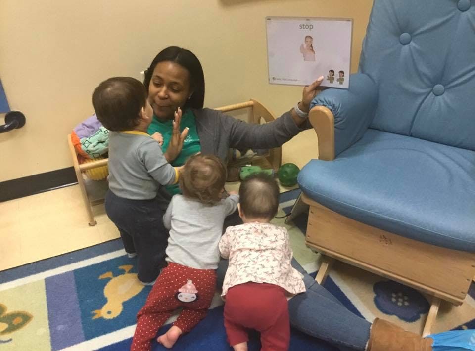 Adult interacting with three children in a classroom