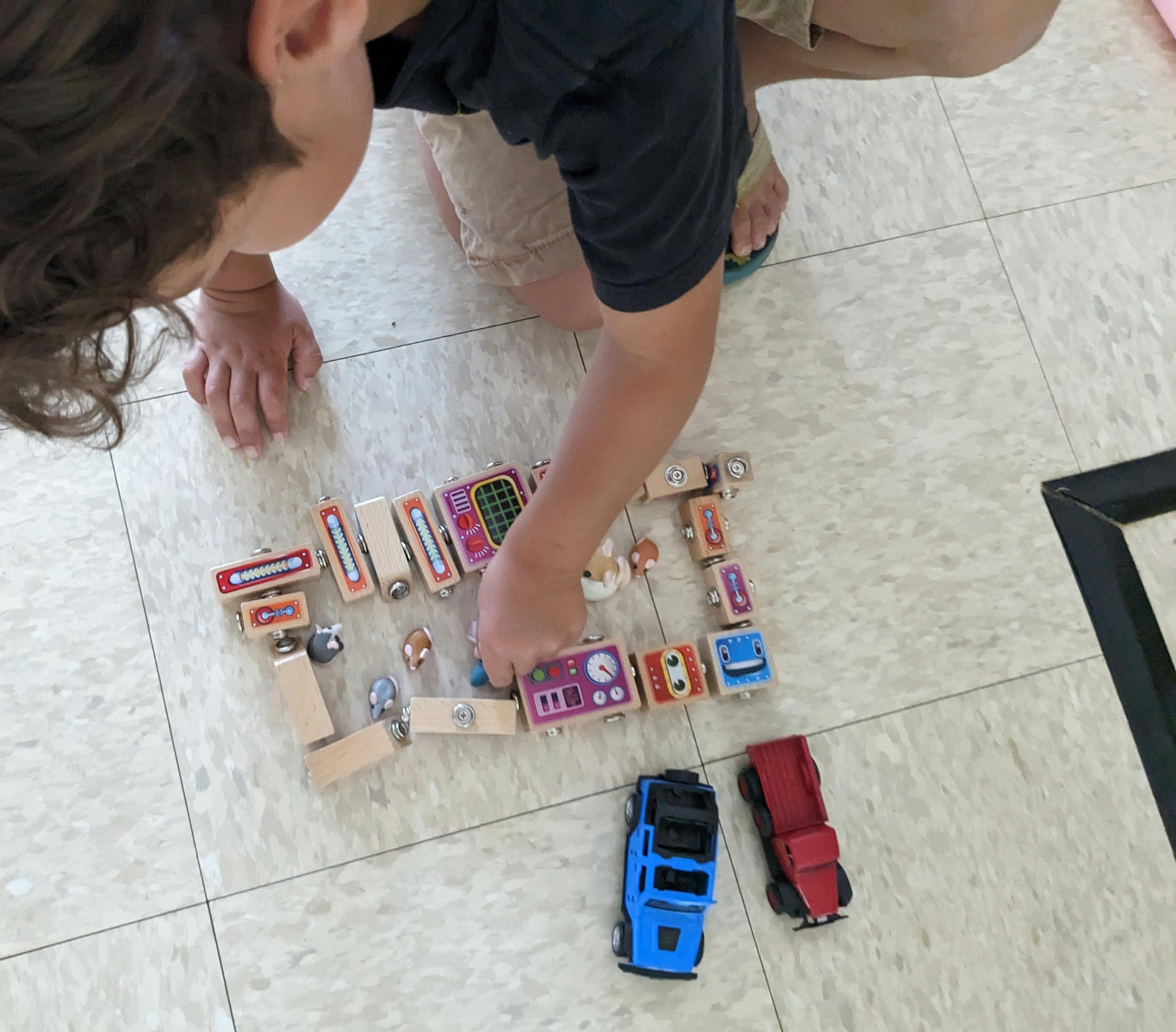 Child playing with wooden blocks and toy cars on the floor