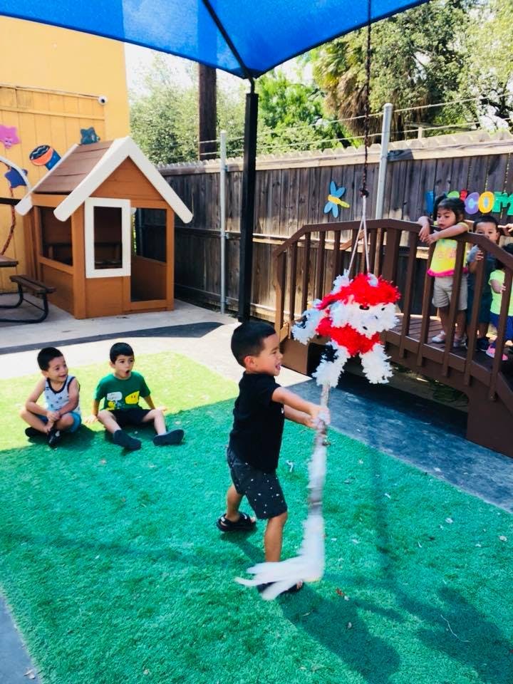 Child hitting a piñata with other children watching in a play area