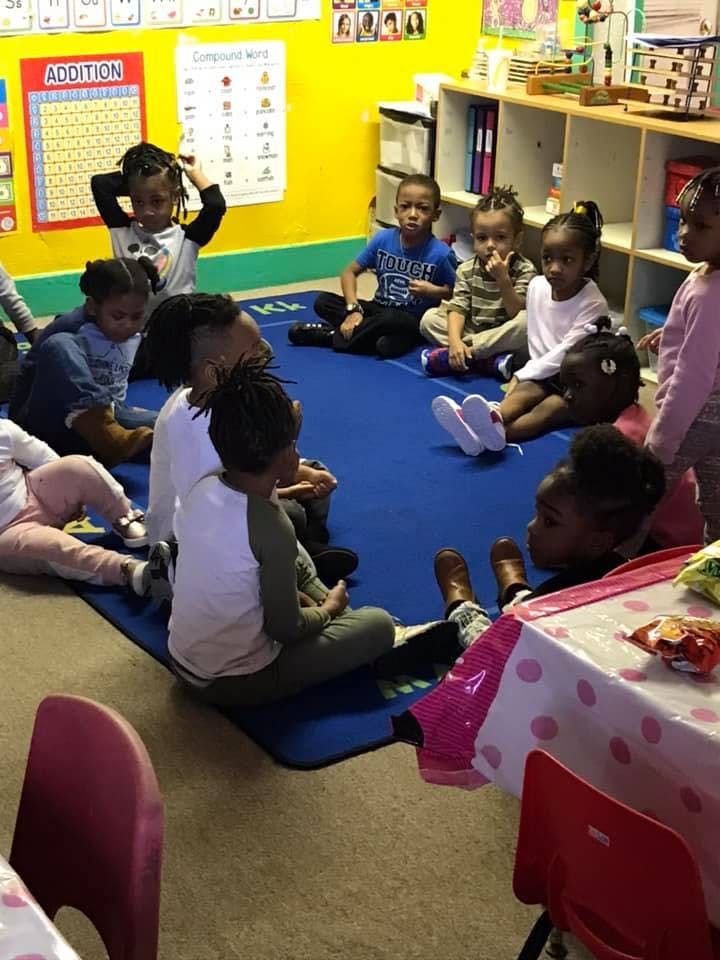 Children sitting on a blue mat in a classroom