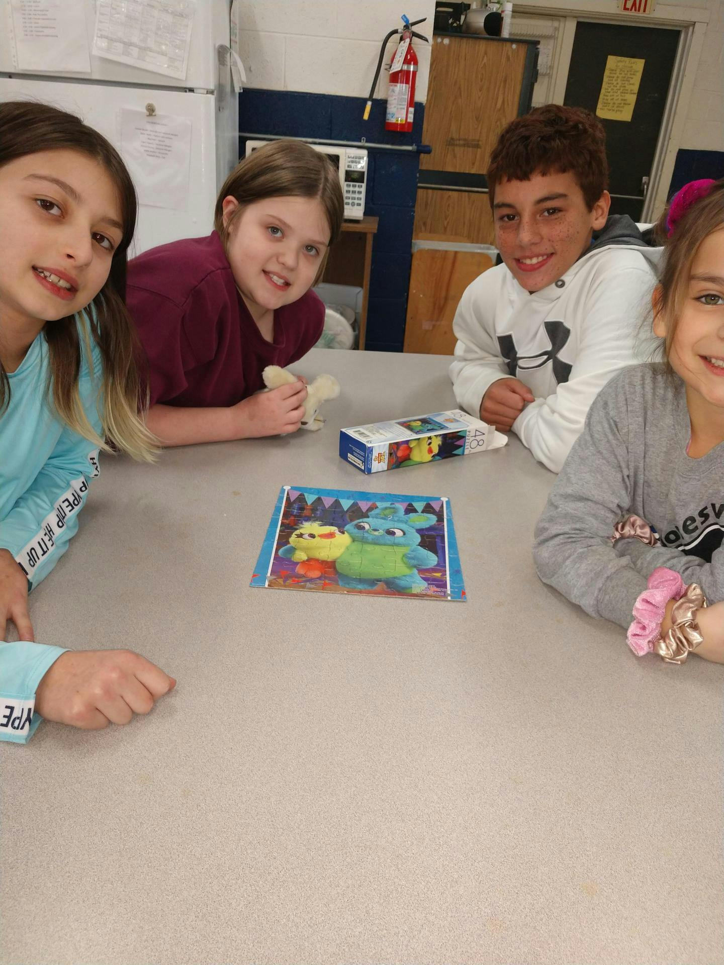 Four children sitting around a table with a picture and a box on it