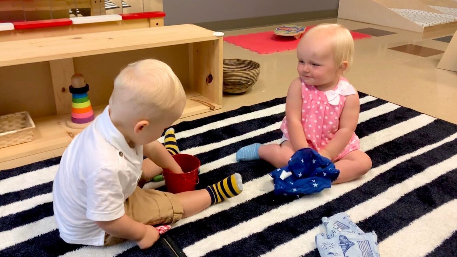 Two children playing on a striped rug
