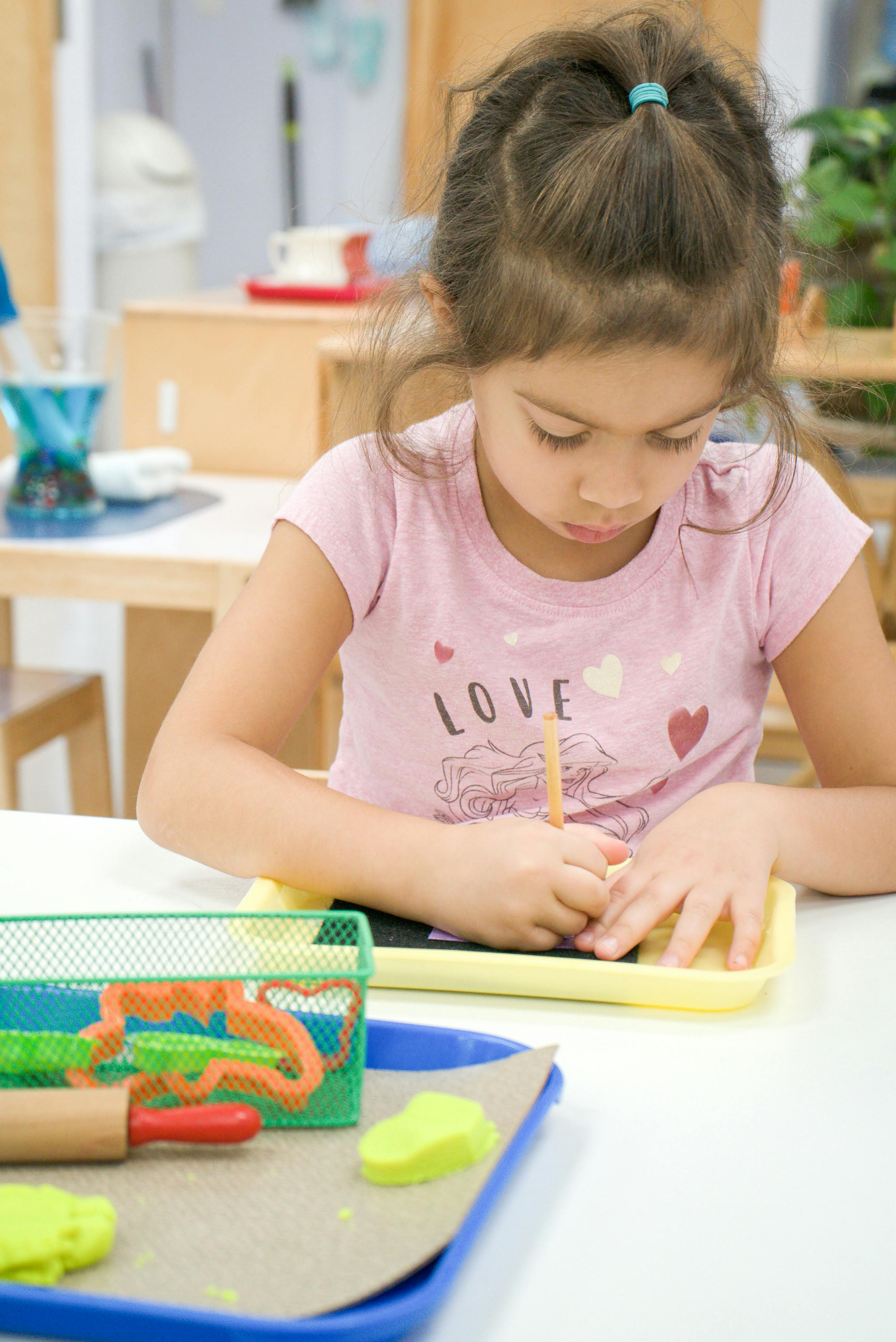 Child writing on a small slate with a pencil