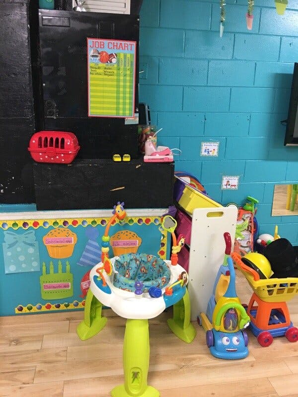 Child's activity center and toys in a room with a "Job Chart" on the wall